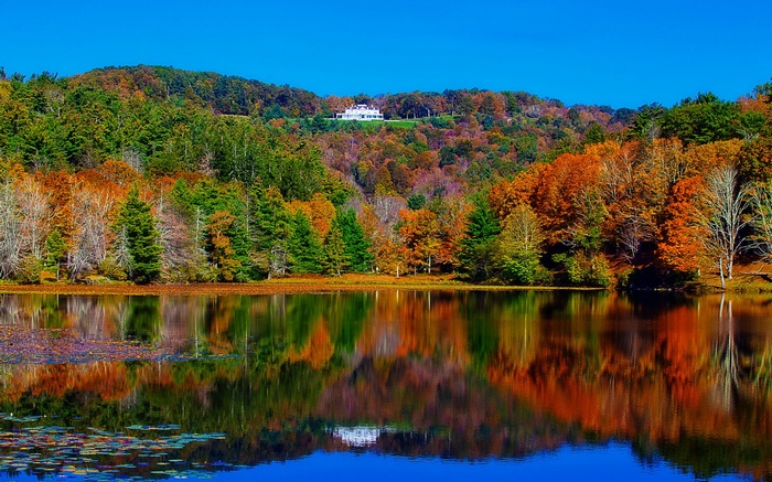 White house on a hill overlooking a lake in autumn