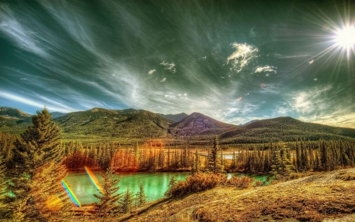 HDR landscape of mountains, forest, and river with sun rays