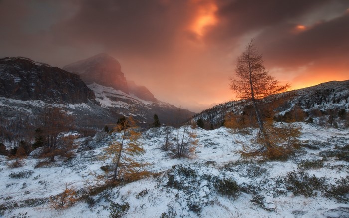 Snowy mountain landscape at sunset with dramatic clouds