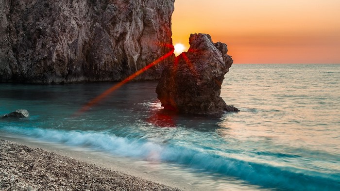 Sunset over the sea with rock formations and waves