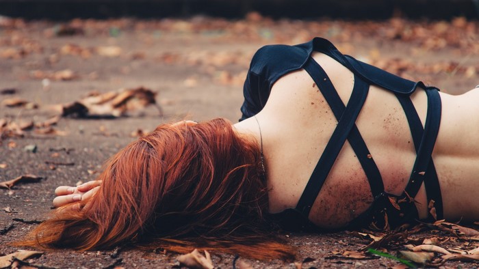 Woman with red hair lying on the ground outdoors