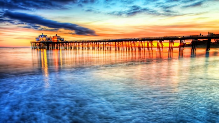 Pier at sunset over the ocean with reflections