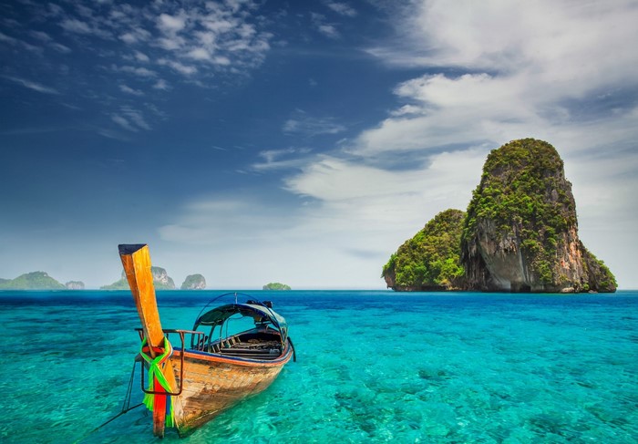Long tail boat in turquoise water near islands
