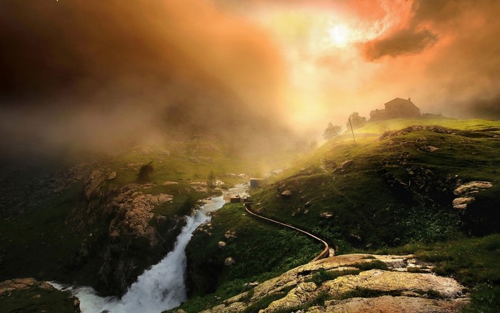Misty mountain landscape with a river and a cabin