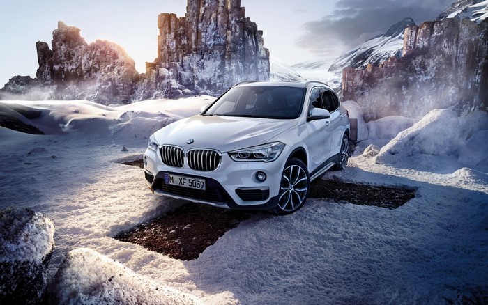 White BMW X1 in a snowy mountain landscape