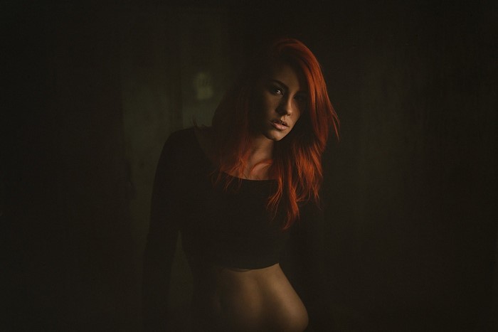 Redhead woman in black crop top in darkness