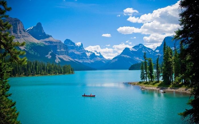 Canoe on a turquoise lake with mountains and pine trees