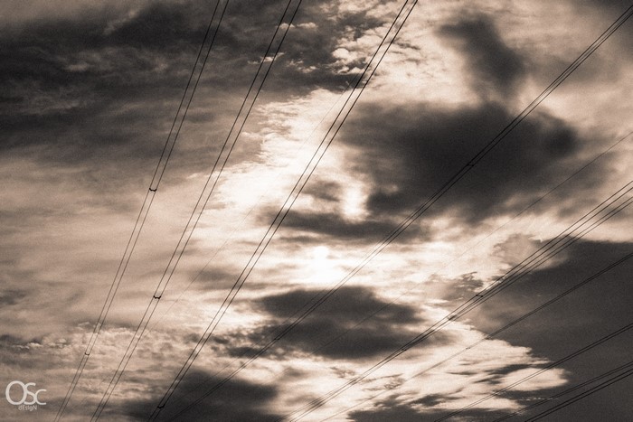 Power lines against a cloudy sky with sunlight