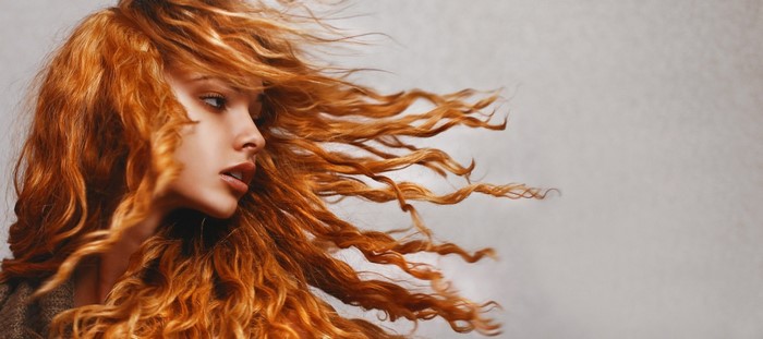 Woman with long, wavy red hair blowing in the wind