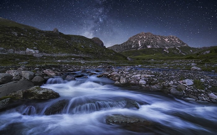 Mountain stream under a starry night sky
