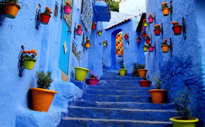 Blue alley with colorful flower pots and stairs