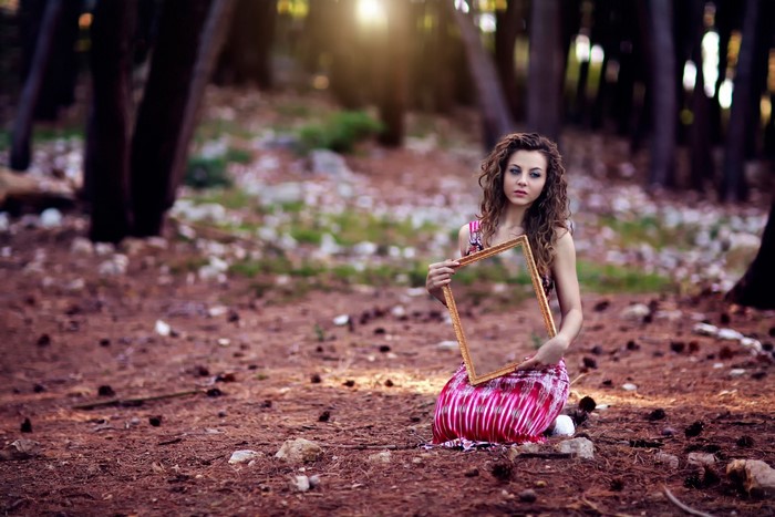 Woman holding a golden frame in a forest