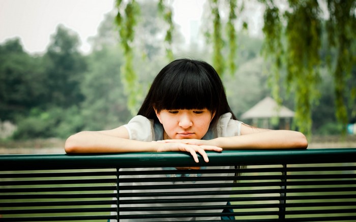 Young Asian woman sitting on a park bench