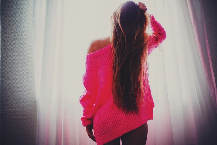 Woman with long hair wearing a pink sweater
