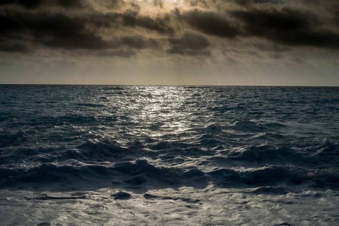 Ocean waves under cloudy sky with sunlight