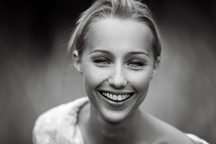 Monochrome portrait of a smiling woman with freckles