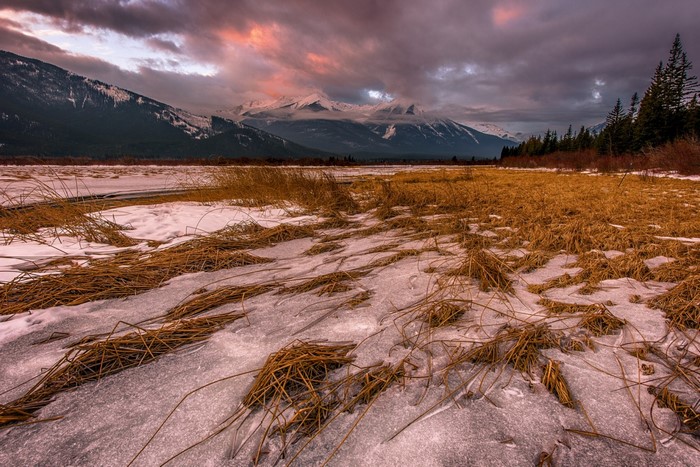 Winter landscape with mountains and frozen lake at sunrise