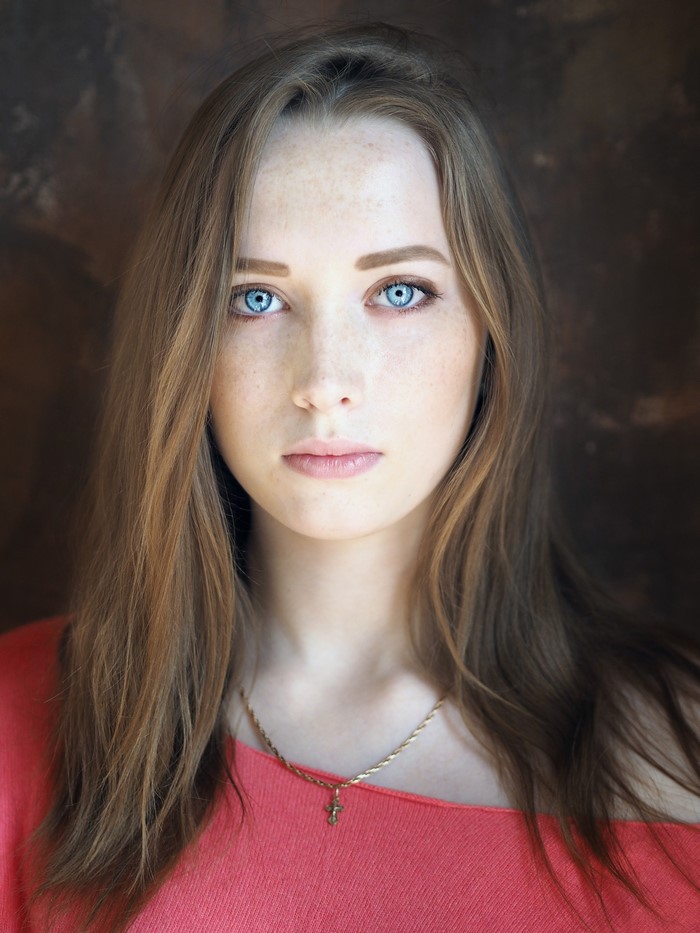 Portrait of a young woman with blue eyes and freckles