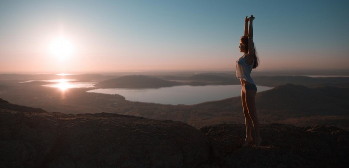 Woman stretching on mountain summit at sunrise
