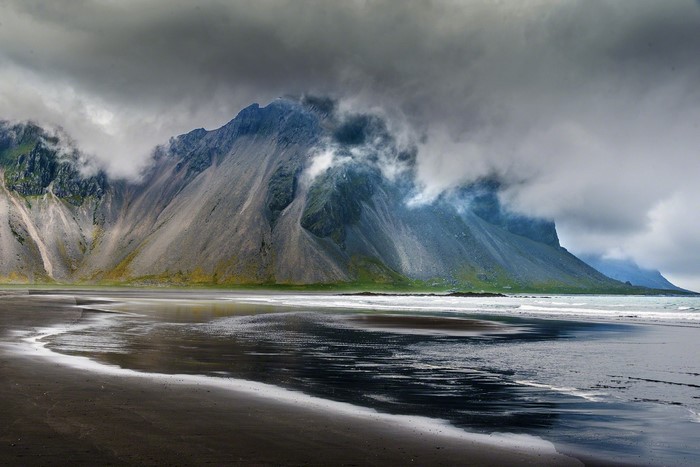 Black sand beach with mountains and clouds