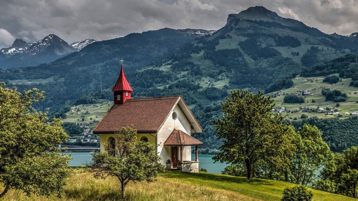 Chapel on a hill with mountains and a lake