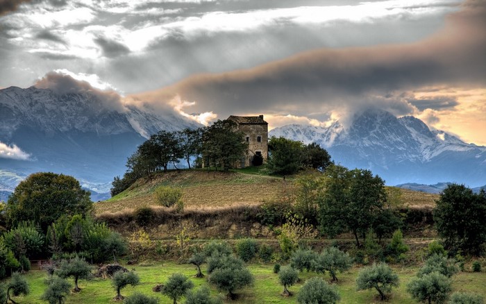 Old house on a hill with mountains and trees
