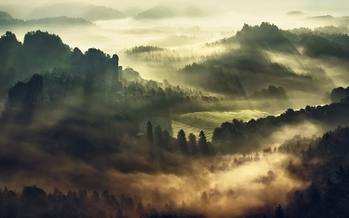 Misty mountain landscape with sunbeams at sunrise