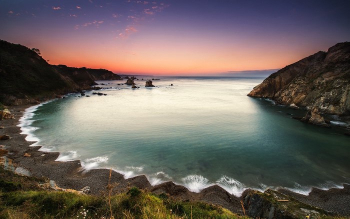 Coastal bay at sunset with rocky cliffs and calm water