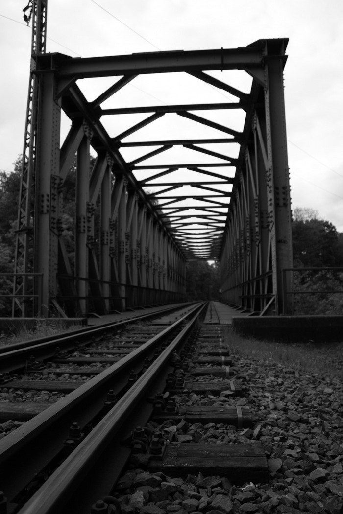 Monochrome image of a steel railway bridge with tracks