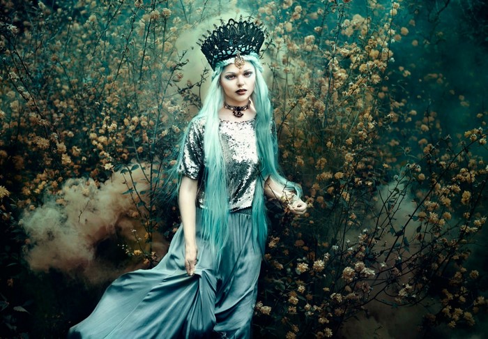 Woman with blue hair and crown in a fantasy forest