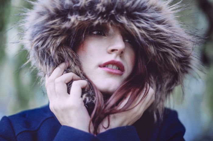 Woman in fur hood holding her face