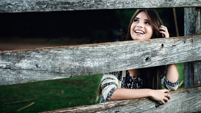 Young woman smiling behind a wooden fence