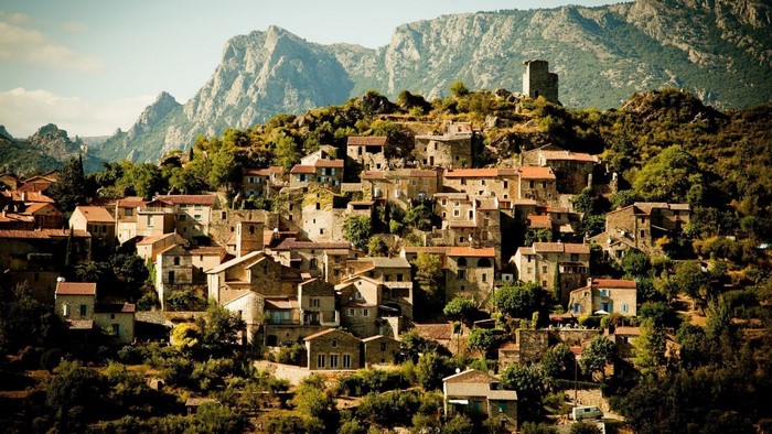 Village nestled in mountains with ancient tower