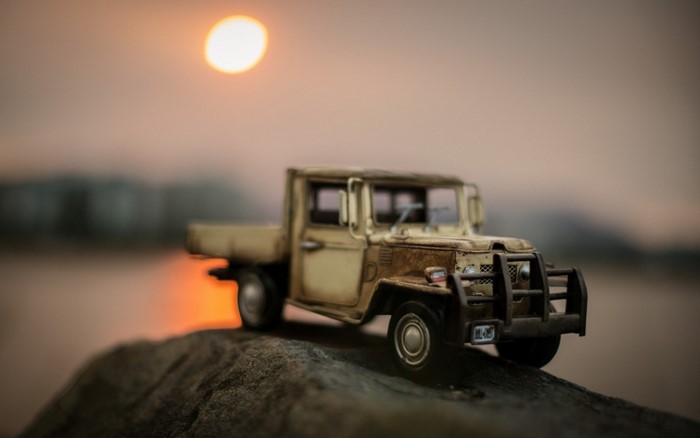 Toy pickup truck on a rock at sunset