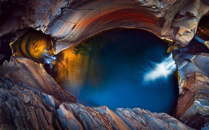 Natural pool with waterfall and colorful rock formations