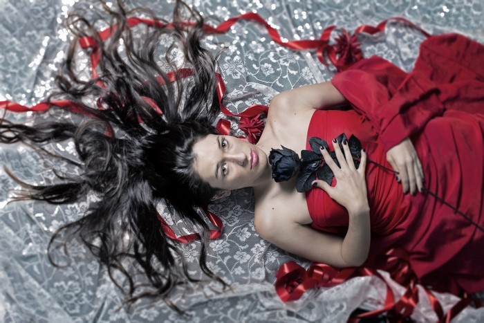 Woman in red dress holding black rose