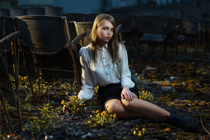 Woman sitting in abandoned theater with yellow flowers