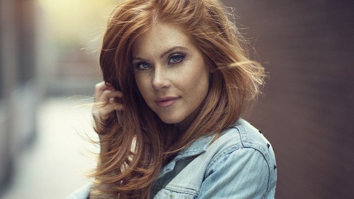 Woman with red hair and freckles wearing a denim jacket