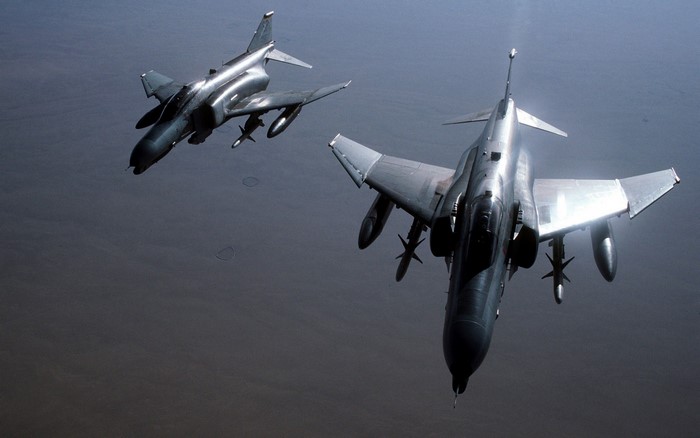 Two F-4 Phantom II fighter jets flying over a desert
