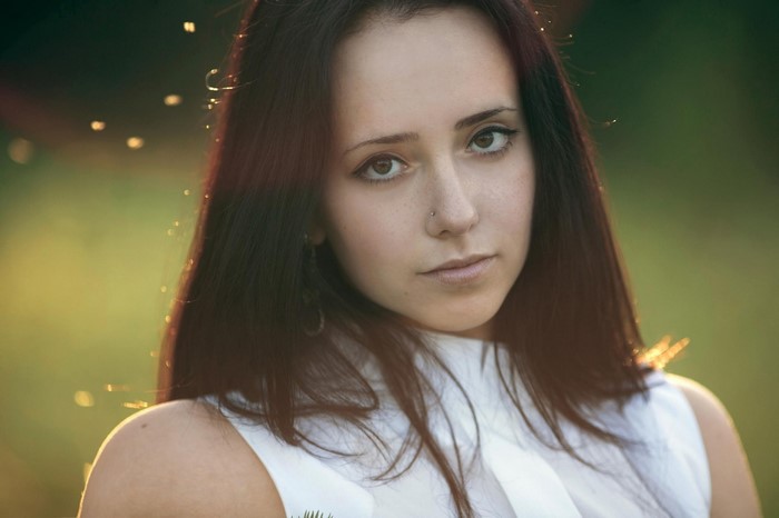 Woman with long dark hair and nose piercing looking at viewer
