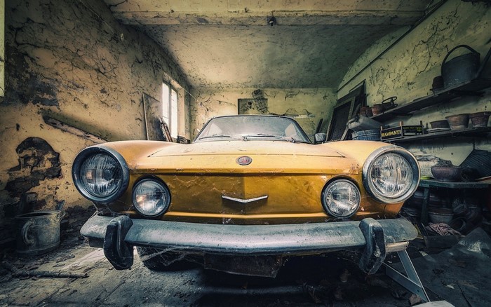 Yellow vintage Fiat convertible in a derelict garage