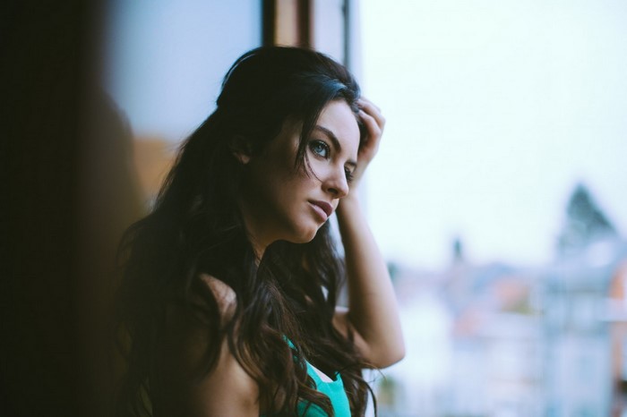 Woman with long dark hair looking out a window