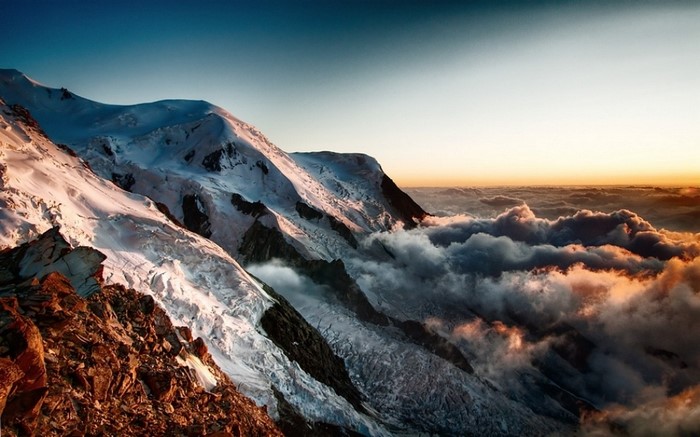 Snowy mountains at sunrise over clouds