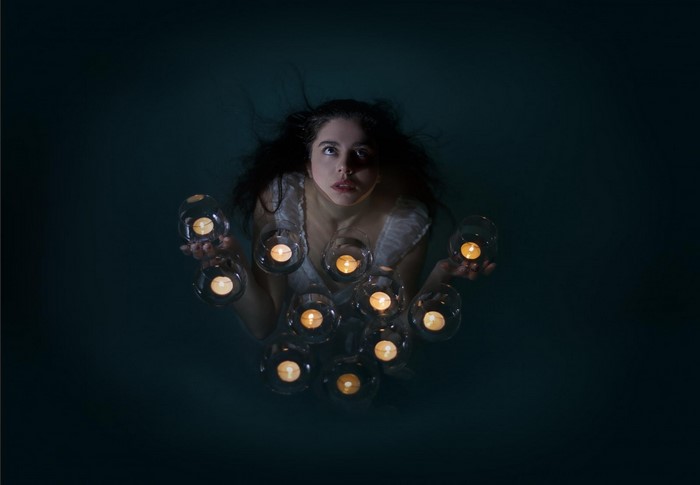 Woman holding candles in dark water