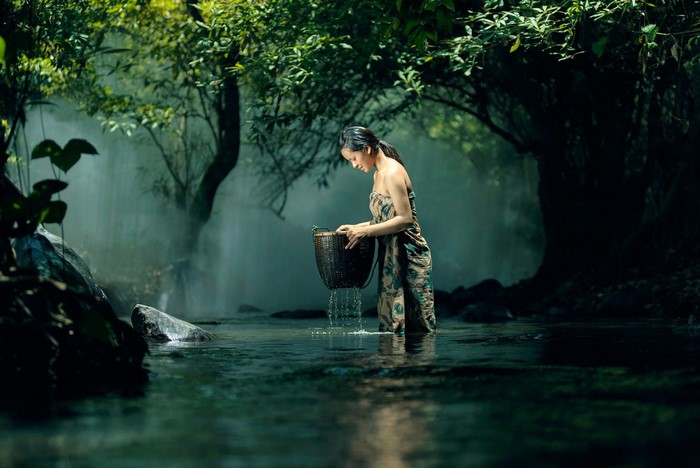 Woman in a forest by a waterfall
