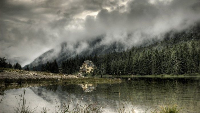 Yellow house by a misty lake and forest