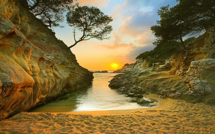 Sunset over a rocky cove with a sandy beach