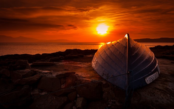 Boat on rocky shore at sunset