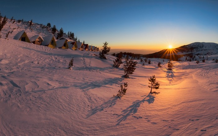 Winter sunset over snowy mountain cabins