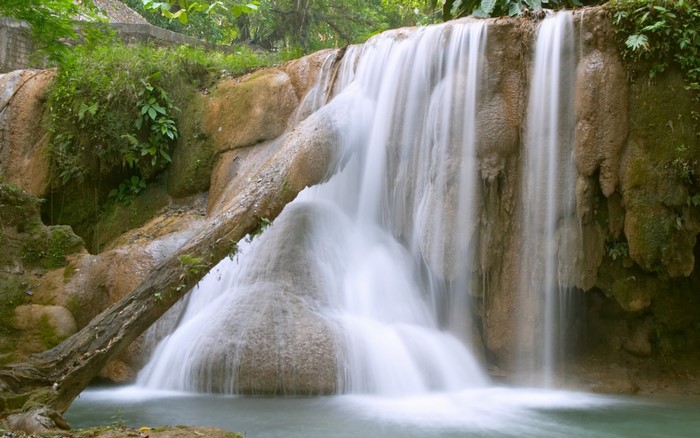 Waterfall cascading over rocks with a fallen tree